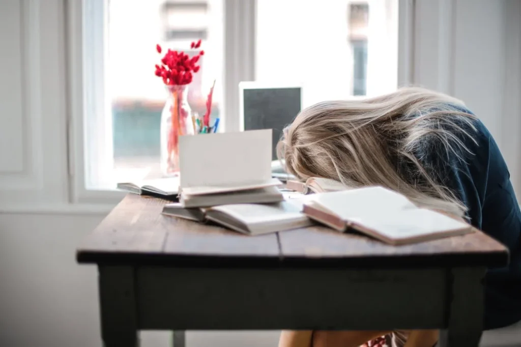 Student exhausted after studying at desk with books Student exhausted after studying at desk with books