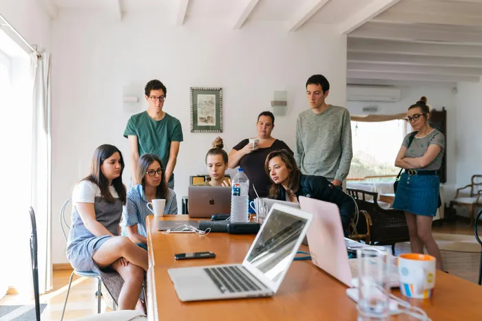 Group of students discussing assignments on laptops in a modern bright office